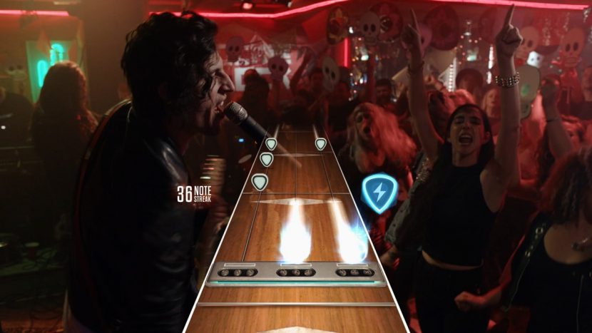 A screenshot from Guitar Hero Live shows the game highway and live action crowds.